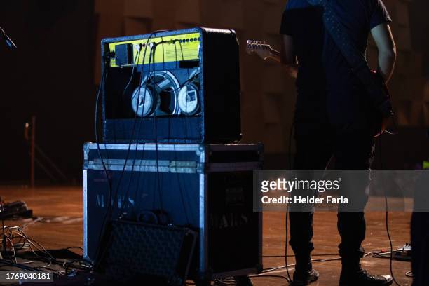 guitarist playing standing on a wooden floor stage seen from behind, beside him a cube amplifier on an equipment case. the musician wears "type" all star tennis shoes - black cube stock pictures, royalty-free photos & images