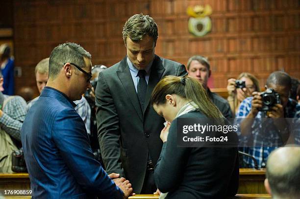Oscar Pistorius prays with sister Aimee and brother Carl before he appears in the Pretoria Magistrates court on August 19 in Pretoria, South Africa....