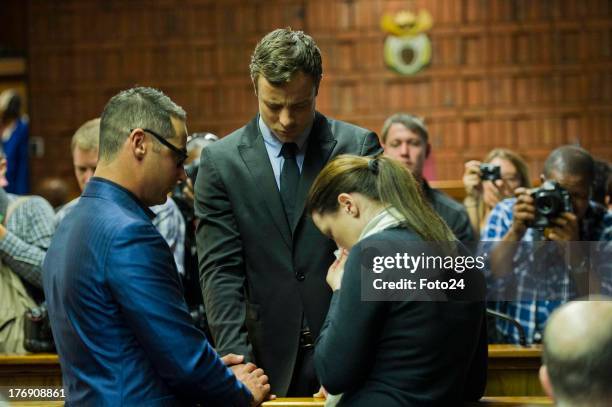 Oscar Pistorius prays with sister Aimee and brother Carl before he appears in the Pretoria Magistrates court on August 19 in Pretoria, South Africa....