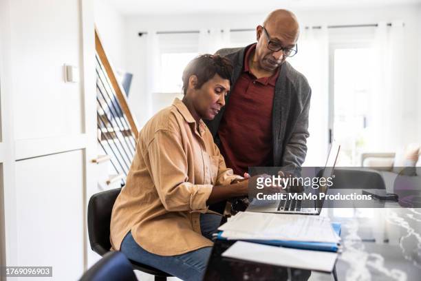 senior couple using laptop and paying bills at home - cream coloured jacket stock pictures, royalty-free photos & images