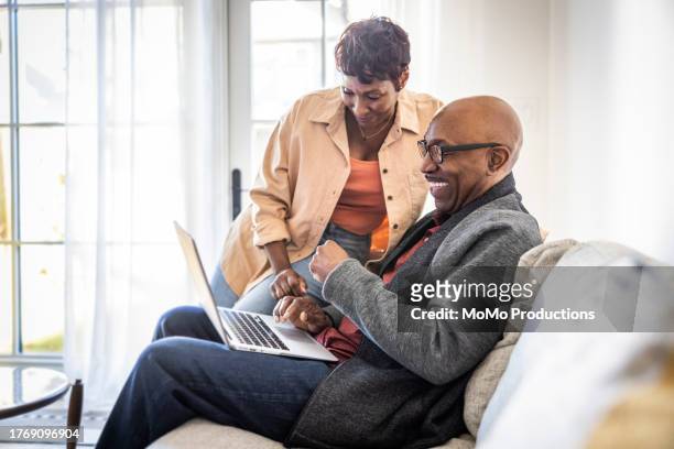 senior couple using laptop at home - cream coloured jacket stock pictures, royalty-free photos & images