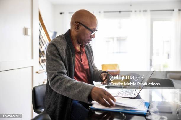 senior man using laptop and paying bills at home - pensioen thema stockfoto's en -beelden
