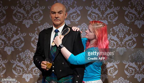 Wardrobe assistant Jane Anderson poses as she brushes a wax figure of British actor Sean Connery wearing a traditional Scottish kilt to mark his 83rd...