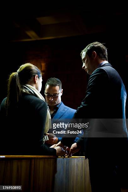 Oscar Pistorius prays with sister Aimee and brother Carl before he appears in the Pretoria Magistrates court on August 19 in Pretoria, South Africa....
