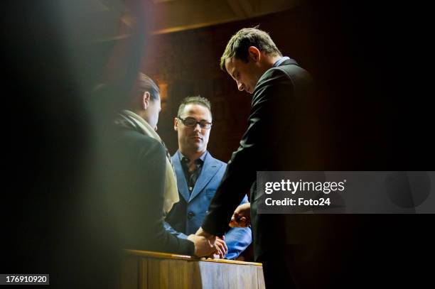 Oscar Pistorius prays with sister Aimee and brother Carl before he appears in the Pretoria Magistrates court on August 19 in Pretoria, South Africa....