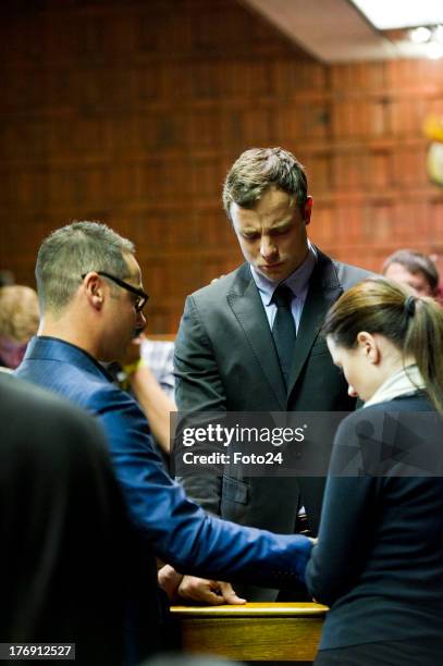 Oscar Pistorius prays with sister Aimee and brother Carl before he appears in the Pretoria Magistrates court on August 19 in Pretoria, South Africa....