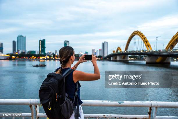 digital nomad taking a photo of the city of da nang, vietnam. - han river stock-fotos und bilder