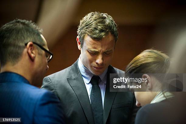 Oscar Pistorius prays with sister Aimee and brother Carl before he appears in the Pretoria Magistrates court on August 19 in Pretoria, South Africa....