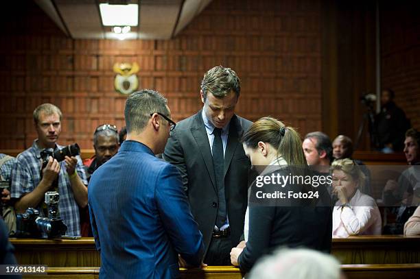 Oscar Pistorius prays with sister Aimee and brother Carl before he appears in the Pretoria Magistrates court on August 19 in Pretoria, South Africa....