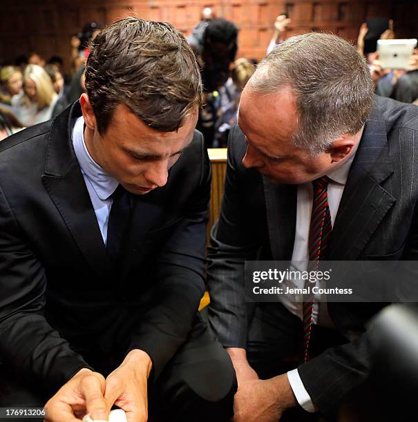 South African athlete Oscar Pistorius speaks with his lawyer Kenny Oldwage in Pretoria Magistrates Court prior to an indictment hearing on August 19,...