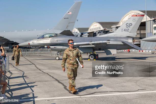 Military personnel walking in front of the fighter jet. General Dynamics F-16 fighter jet on the tarmac at the static display during the...