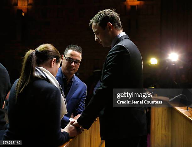 South African athlete Oscar Pistorius prays with his brother Carl Pistorius and his sister Aimee Pistorius prior to his indictment hearing in...