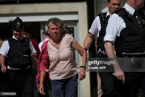 Police officers detain a climate protester after she and other demonstrators blocked the entrance to the office building housing PR company Bell...