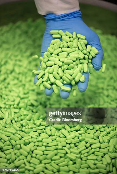 An employee collects a handful of Pentalgin tablets from a storage bin at OAO Pharmstandard's Leksredstva drug manufacturing unit in Kursk, Russia,...