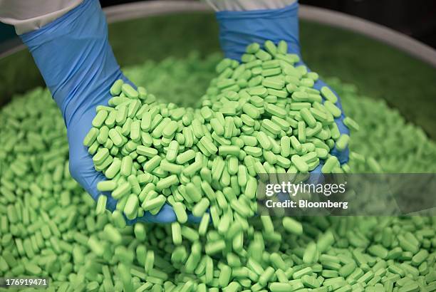 An employee collects a handful of Pentalgin tablets from a storage bin at OAO Pharmstandard's Leksredstva drug manufacturing unit in Kursk, Russia,...