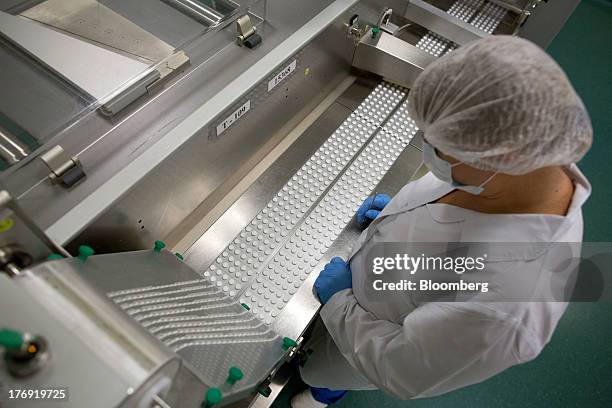 An employee checks sealed packets of Ascophenum-P tablets as they move along the production line at OAO Pharmstandard's Leksredstva drug...