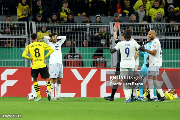 Match referee Harm Osmers shows a red card to Ozan Kabak of TSG 1899 Hoffenheim during the DFB cup second round match between Borussia Dortmund and...