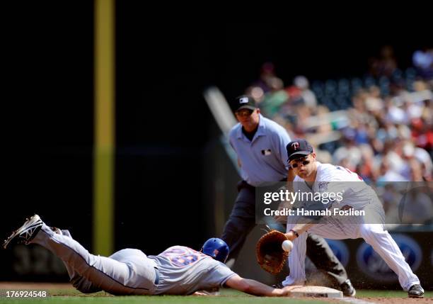 Daniel Murphy of the New York Mets dives back safely to first base as Justin Morneau of the Minnesota Twins fields the ball during the fourth inning...