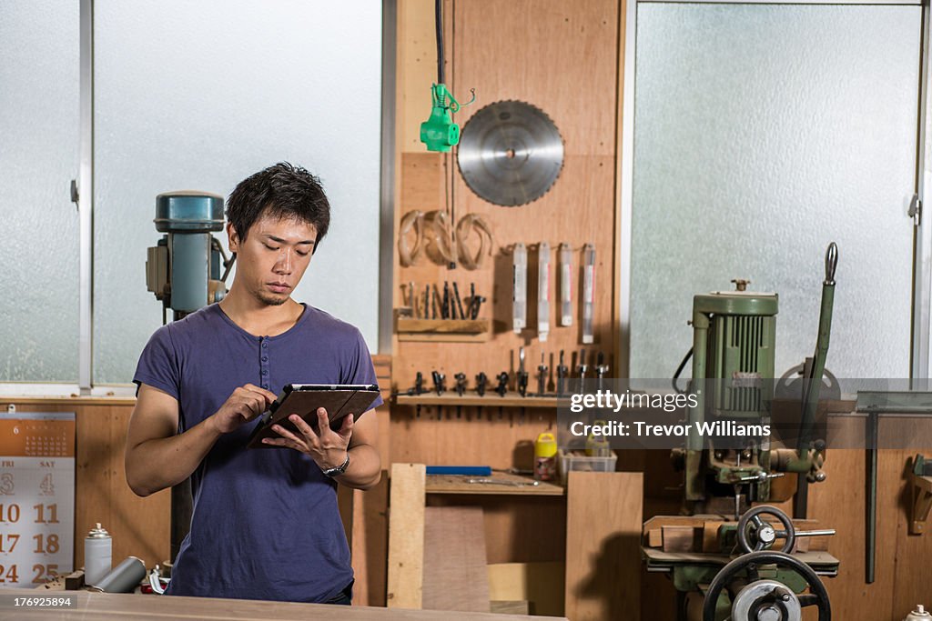 A man standing and using a tablet in a workshop