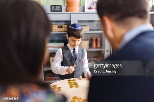 cute little boy playing traditional games during hanukkah - jewish chocolate coins stock pictures, royalty-free photos & images