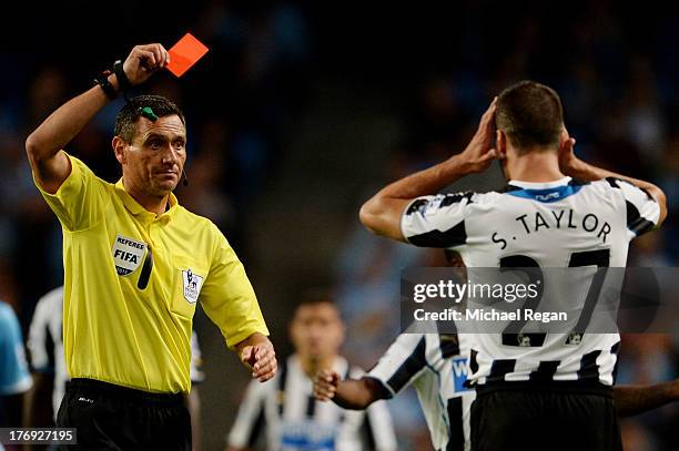 Referee Andre Marriner shows the red card to Steven Taylor of Newcastle United during the Barclays Premier League match between Manchester City and...