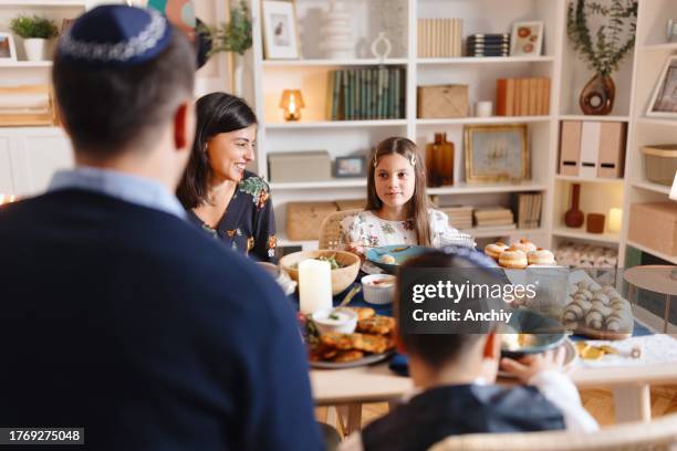smiling jewish people having traditional hanukkah dinner - judeus imagens e fotografias de stock