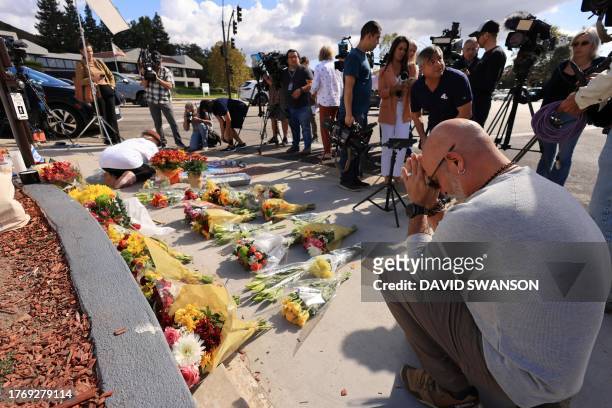 Man prays on November 7, 2023 as flowers and candles are placed at the intersection where a protest the previous day led to the death of a Jewish man...