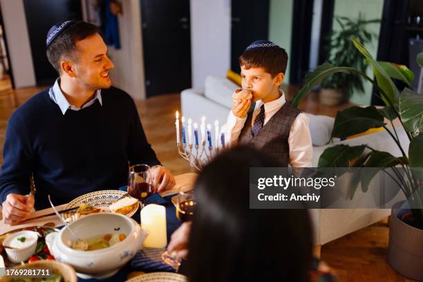 jewish family during traditional hanukkah dinner - sufganiyah stock pictures, royalty-free photos & images