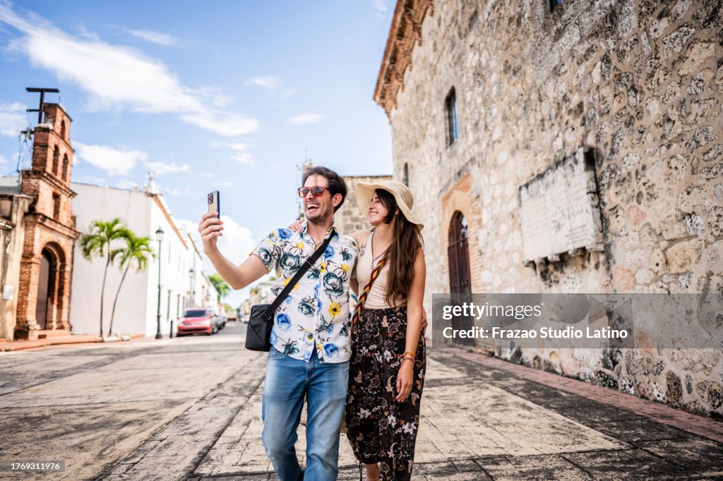 Tourist couple taking a selfie or filming using mobile phone in historic district