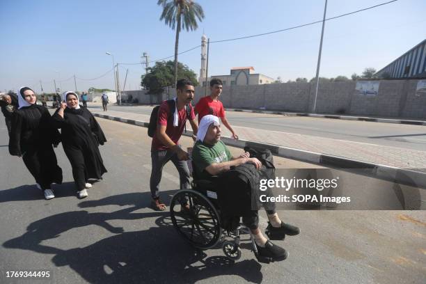 Palestinian man pushes his father in a wheelchair as they flee Gaza City towards the southern areas walking on a road, amid the ongoing battles...