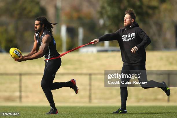 Harry O'Brien of the Magpies handballs whilst being chased by Dane Swan during a Collingwood Magpies AFL training session at Olympic Park on August...