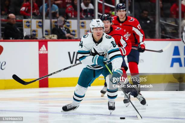 Mikael Granlund of the San Jose Sharks skates with the puck in front of Rasmus Sandin of the Washington Capitals during the third period of the game...