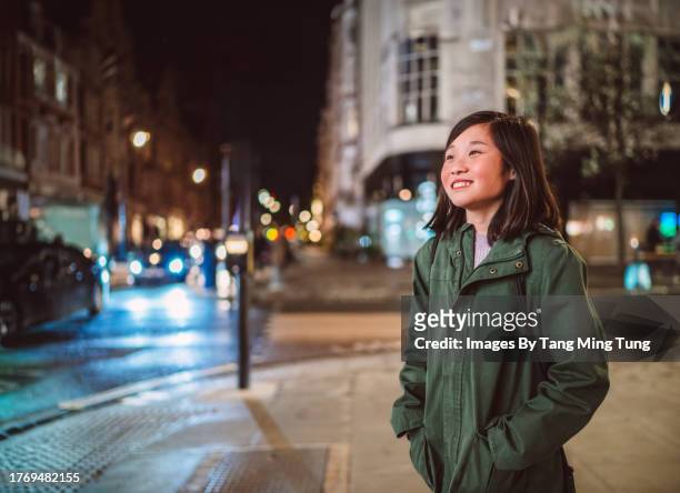 cheerful teenage girl walking in the street while exploring in a town at night - road signal stock pictures, royalty-free photos & images