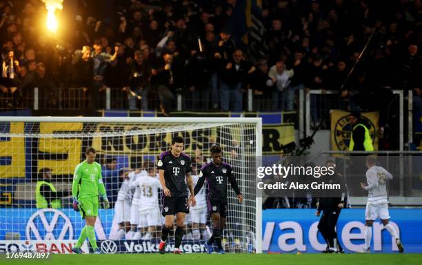 Manuel Neuer, Kim Min-Jae and Kingsley Coman of Bayern Munich look dejected as FC Saarbrücken players celebrate after Marcel Gaus of FC Saarbrücken...