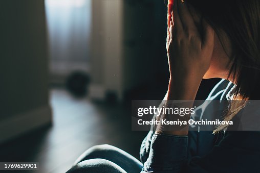 Silhouette of sad and depressed woman sitting on the floor at home Silhouette of sad and depressed woman sitting on the floor at home
