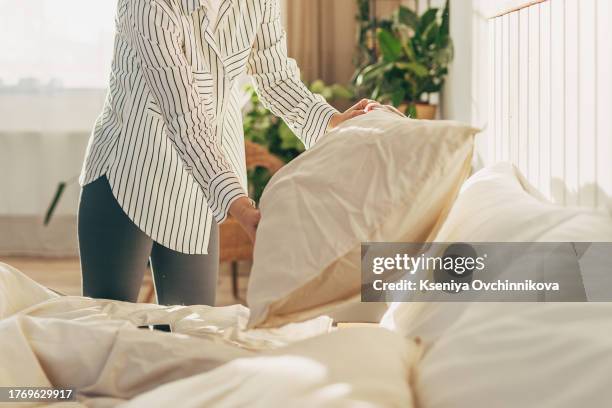 young redhead woman make bed at bedroom - chambre bien rangée photos et images de collection