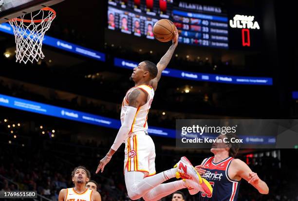 Dejounte Murray of the Atlanta Hawks dunks against Mike Muscala of the Washington Wizards during the second quarter at State Farm Arena on November...