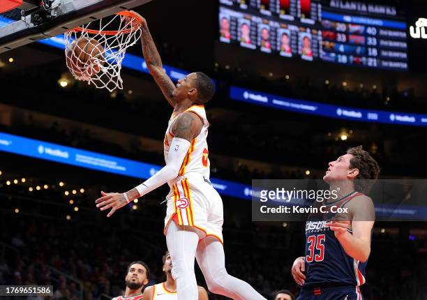 Dejounte Murray of the Atlanta Hawks dunks against Mike Muscala of the Washington Wizards during the second quarter at State Farm Arena on November...