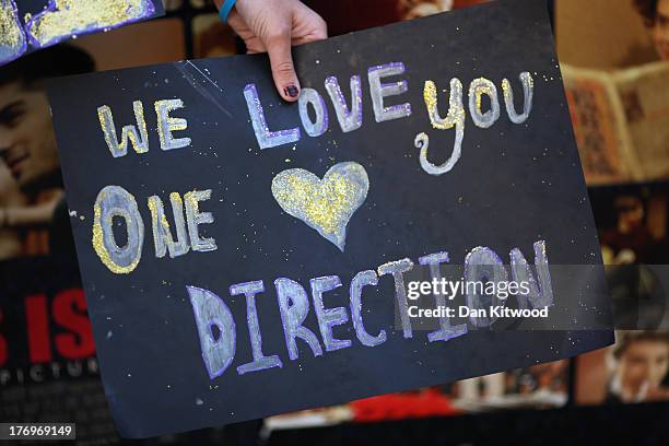One Direction fans wave placards as they take their positions in Leicester Square ahead of the premier to the bands new film on August 20, 2013 in...