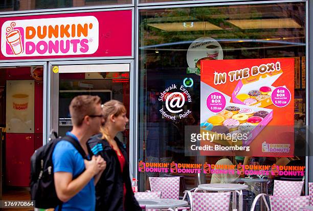 Pedestrians walk past a Dunkin' Donuts store, operated by Dunkin' Brands Group Inc., in Berlin, Germany, on Monday, Aug. 19, 2013. Dunkin' Brands...