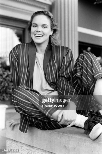 Model poses in a navy ecru and rayon white banker stripe baseball jacket with matching pants over an ecru rayon top.