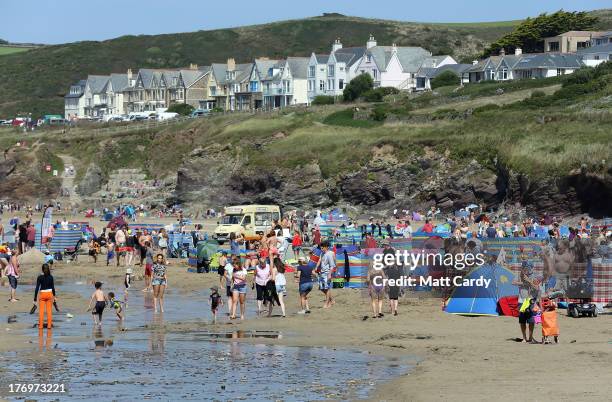 People enjoy the fine summer weather on the beach at Polzeath on August 20, 2013 near Padstow, England. Polzeath is one of the closest beaches to the...
