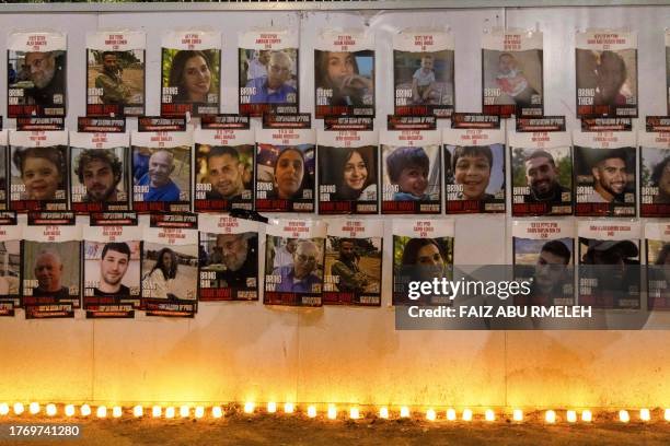 Jerualem, Israel. People light candles beneath a wall showing posters identifying hostages abducted by Palestinian militants during the October 7...