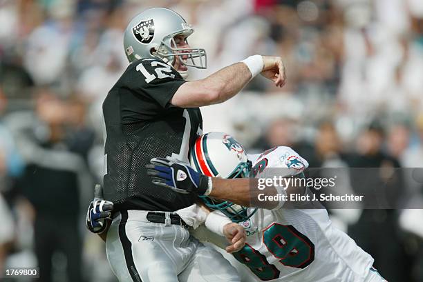 Quarterback Rich Gannon of the Oakland Raiders gets the pass off before he is brought down by Jason Taylor of the Miami Dolphins during the NFL game...