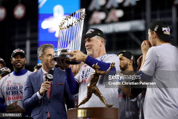 Manager Bruce Bochy of the Texas Rangers hoists the Commissioner's Trophy after the Texas Rangers beat the Arizona Diamondbacks 5-0 in Game Five to...