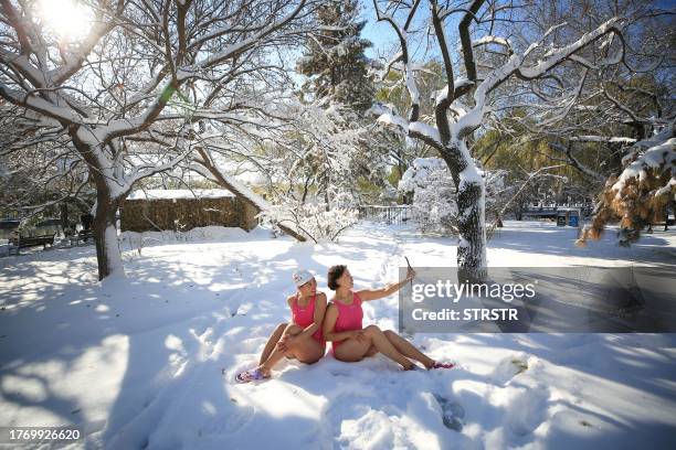This photo taken on November 7, 2023 shows winter swimming enthusiasts taking photos at Beiling Park after snowfall in Shenyang, in China's...