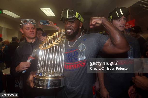 Adolis García of the Texas Rangers celebrates with the Commissioner's Trophy in the clubhouse after the Texas Rangers beat the Arizona Diamondbacks...