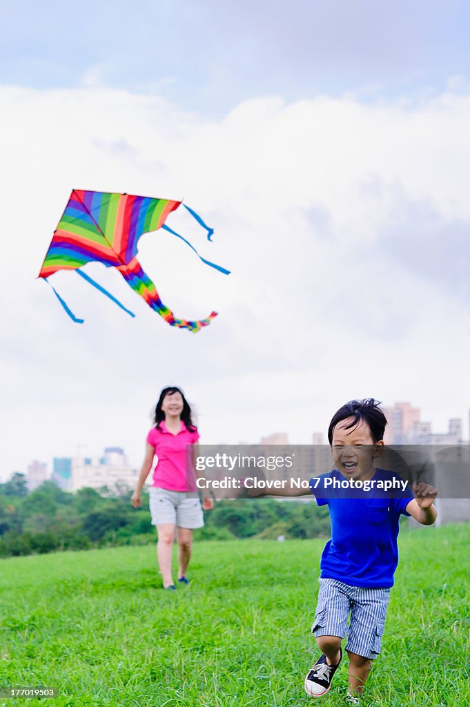 Asian mother and son fly a kite.
