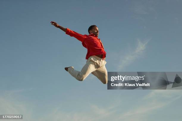 cheerful man jumping high against sky - agile transformation stock pictures, royalty-free photos & images