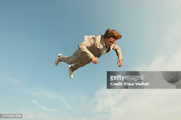 carefree man falling down against sky - cream coloured suit stock-fotos und bilder